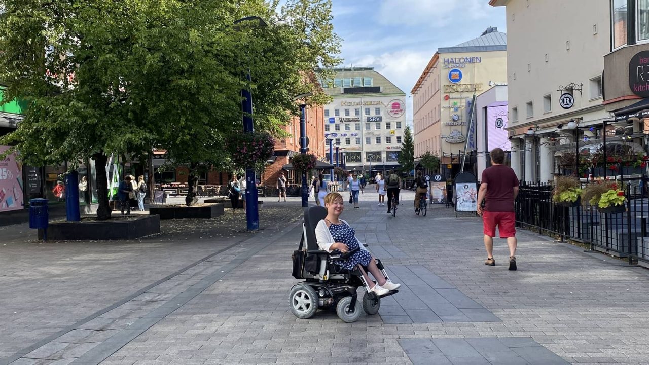 Pyörätuolissa istuva henkilö Jyväskylän keskustassa kävelykadulla.
