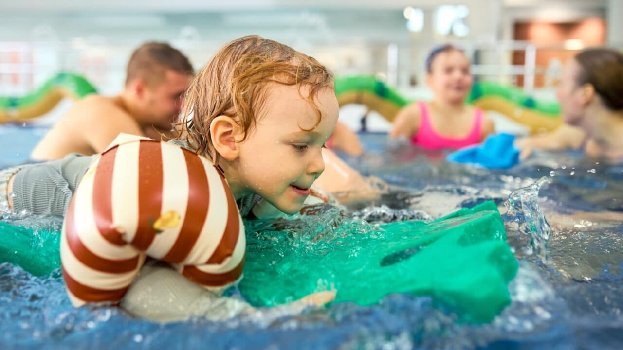 A kid swimming with floats in the AaltoAlvari children's pool.